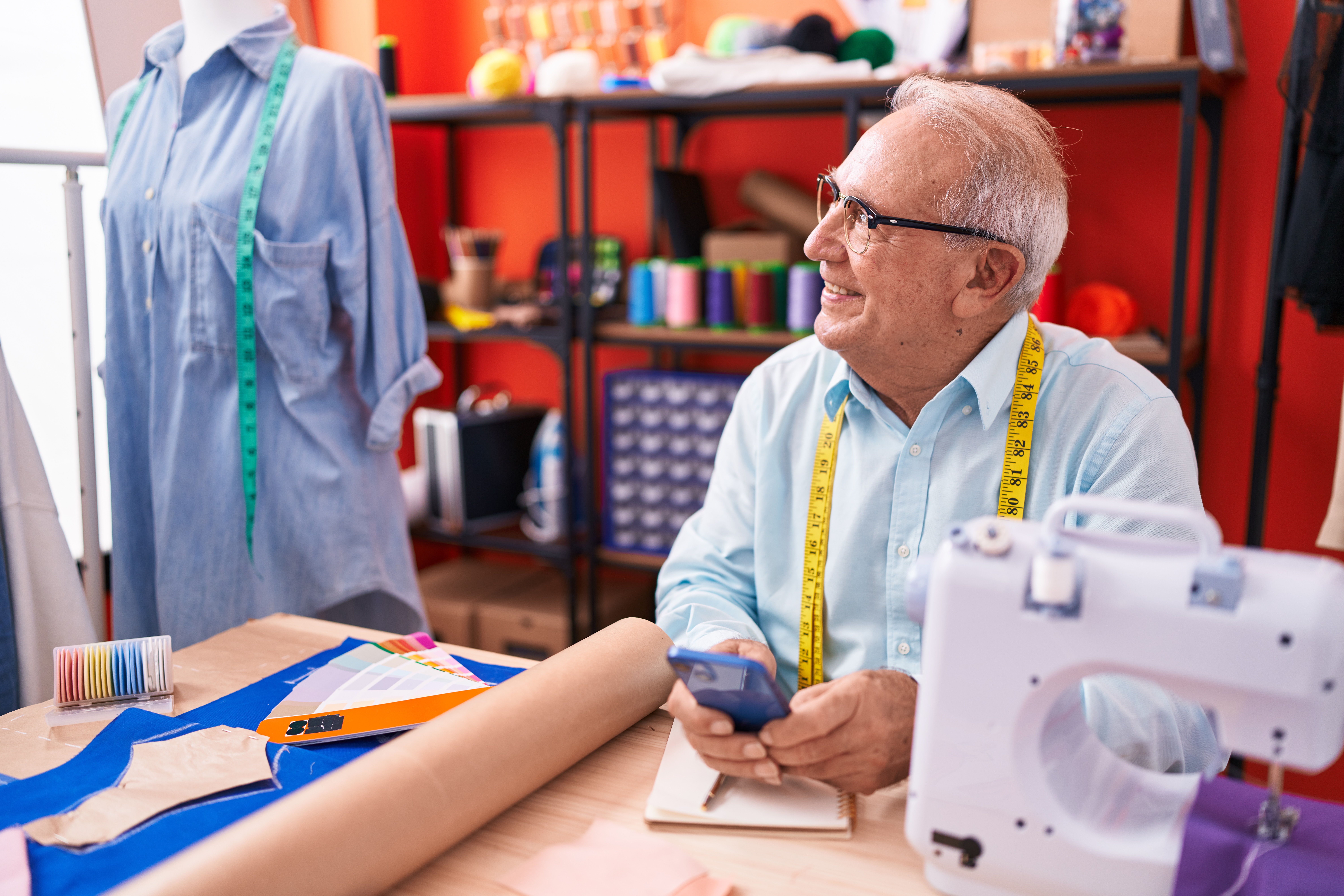 alfaiate-de-cabelos-grisalhos-de-meia-idade-sorrindo-confiante-usando-smartphone-no-atelier.jpg